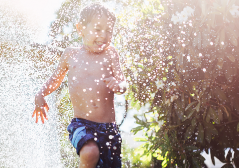 boy running through sprinkler