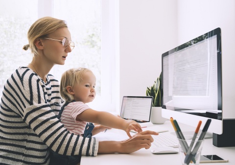 a young work-from-home stay-at-home mom at her computer with her young daughter