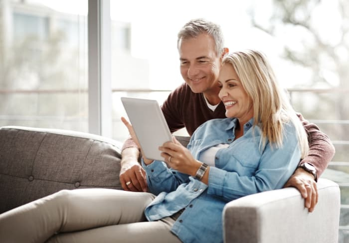 Older couple looking at a tablet screen while sitting on a couch