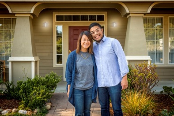 Young Asian couple in front of home