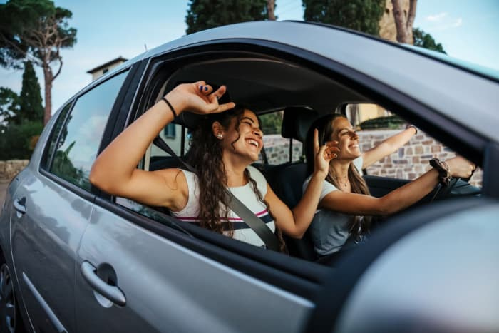 Two girls riding in a car together, enjoying the drive