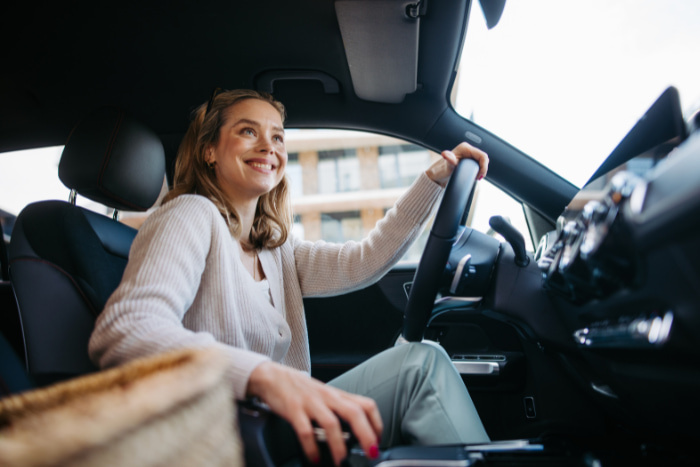 Happy woman driving her new electric car in a city.