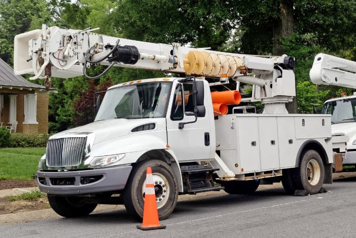 Front and side view of parked communication utility trucks in a residential neighborhood.