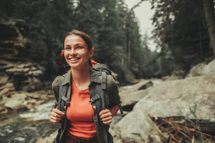 Waist up of a joyful woman traveling in the forest