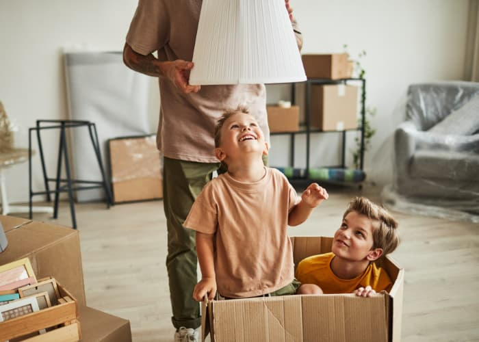 Portrait of two cheerful boys playing in big cardboard box while family moving to new house.