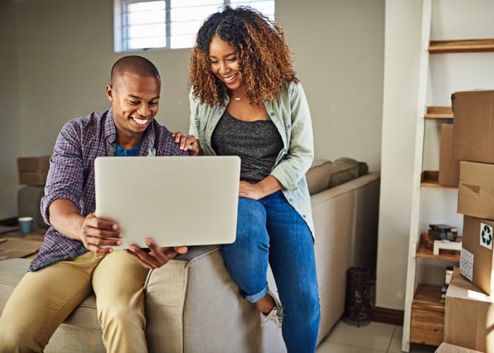 Shot of a cheerful young couple doing online shopping together while being seated on a couch at home.