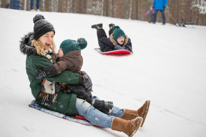 Woman and child on a sled, sliding down a hill