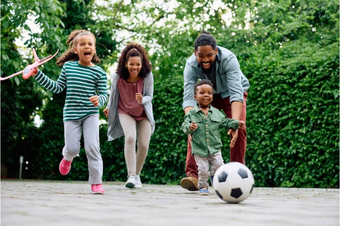 Happy African American family has fun while playing together outdoors.