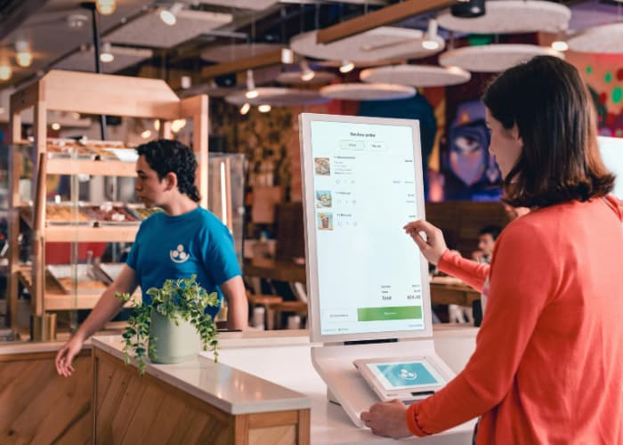 A woman in a red cardigan using the Clover Kiosk