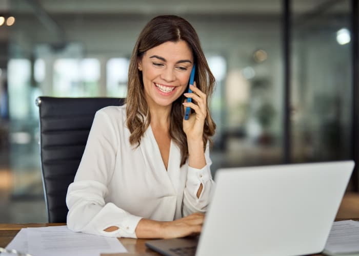 Happy mature business woman talking on phone making business call in office.
