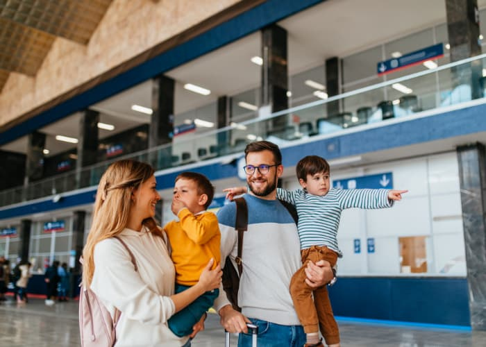 Happy young family with luggage in airport go together on vacation.