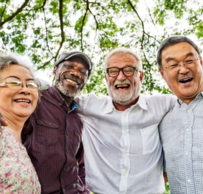 Elderly friends smiling under a tree