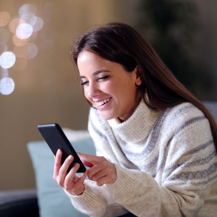 young woman smiling and looking at her phone