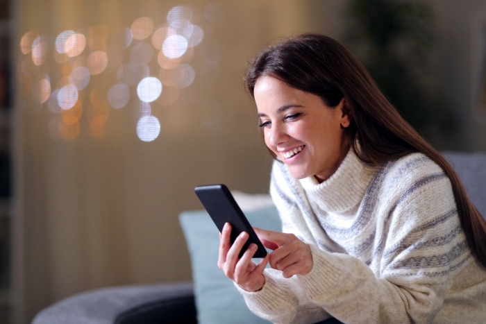 smiling woman in long sleeved sweater looking at phone