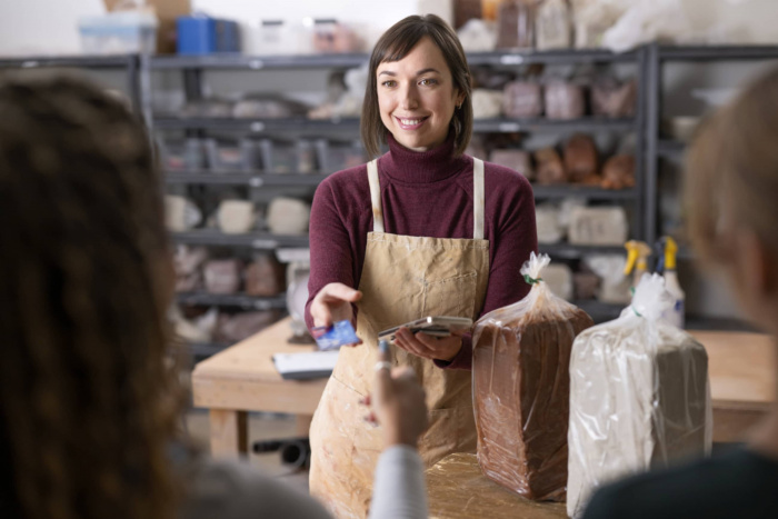woman in shop apron swiping card for customer purchase