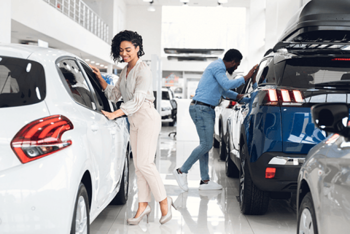 Couple looking at new cars on display inside a dealership