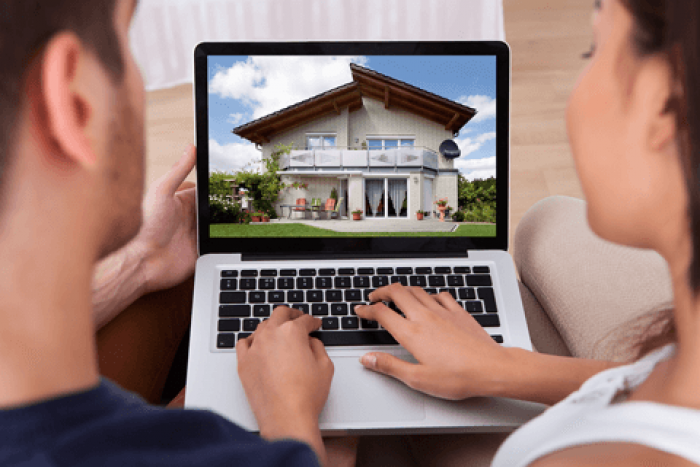 a couple browsing homes for sale on a laptop