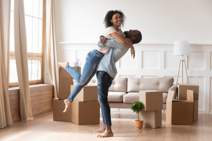 first time home buyer couple embraces in their new living room