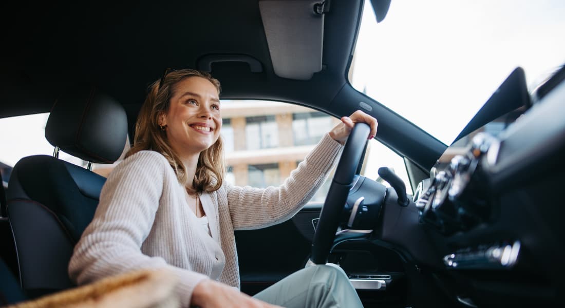 Happy woman driving her new electric car in a city.