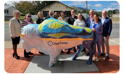 A group of people standing behind a buffalo sculpture with the Chartway logo