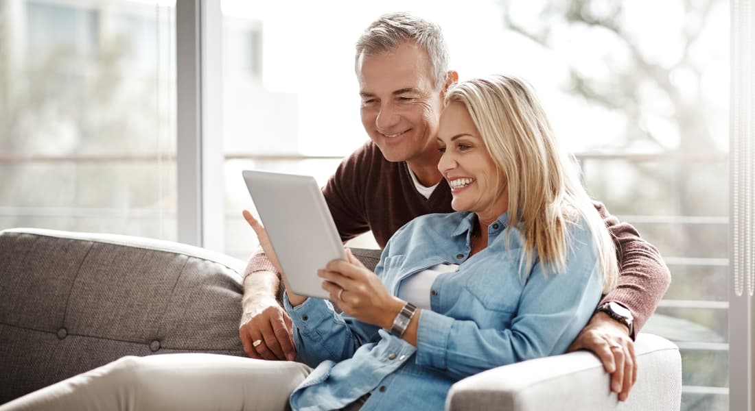 Older couple looking at a tablet screen while sitting on a couch