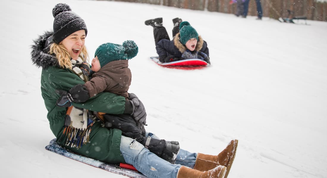 Mother and son sliding on a sled down a hill covered in snow